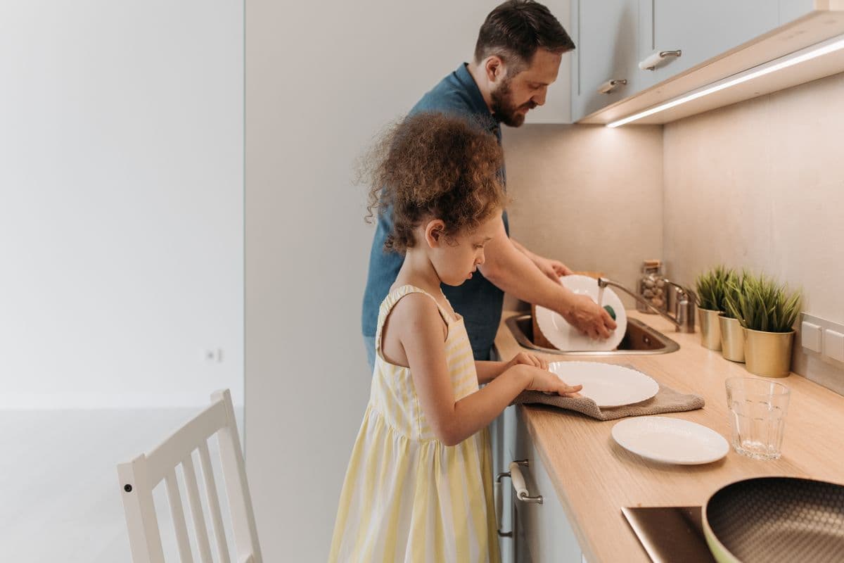A child helping wash dishes in the kitchen