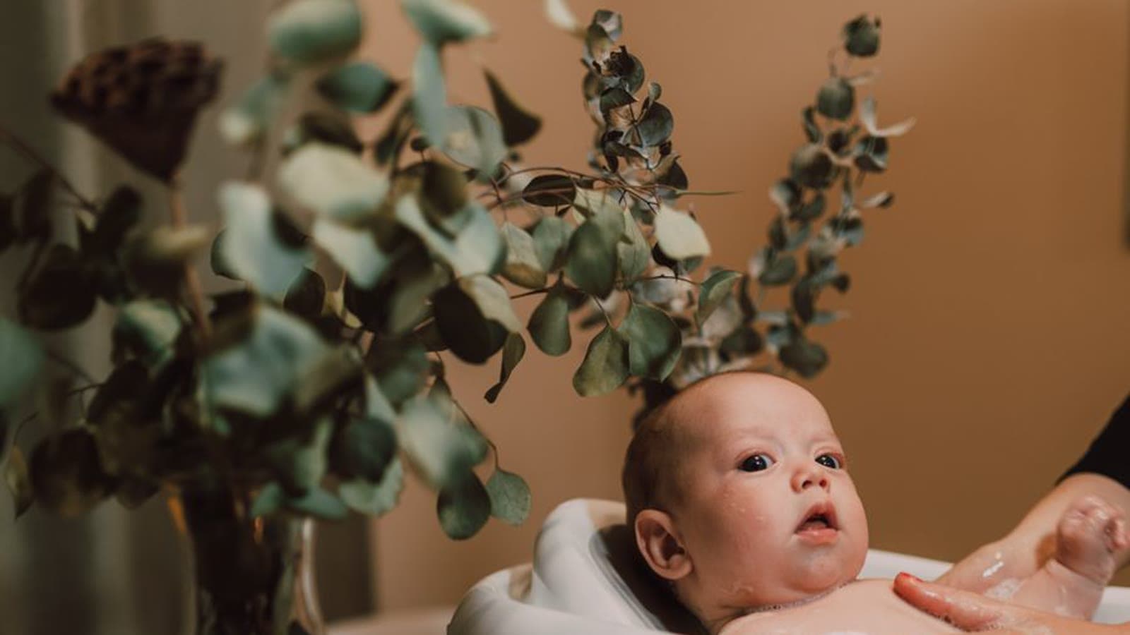 A baby sitting in a small white bathtub
