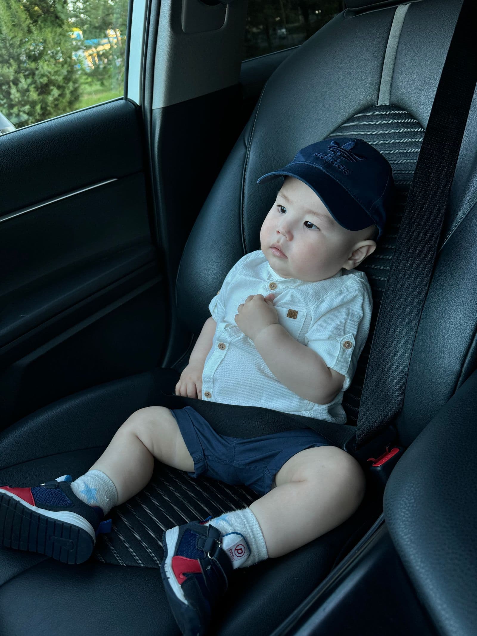 A toddler buckled into a car seat in the back of a car