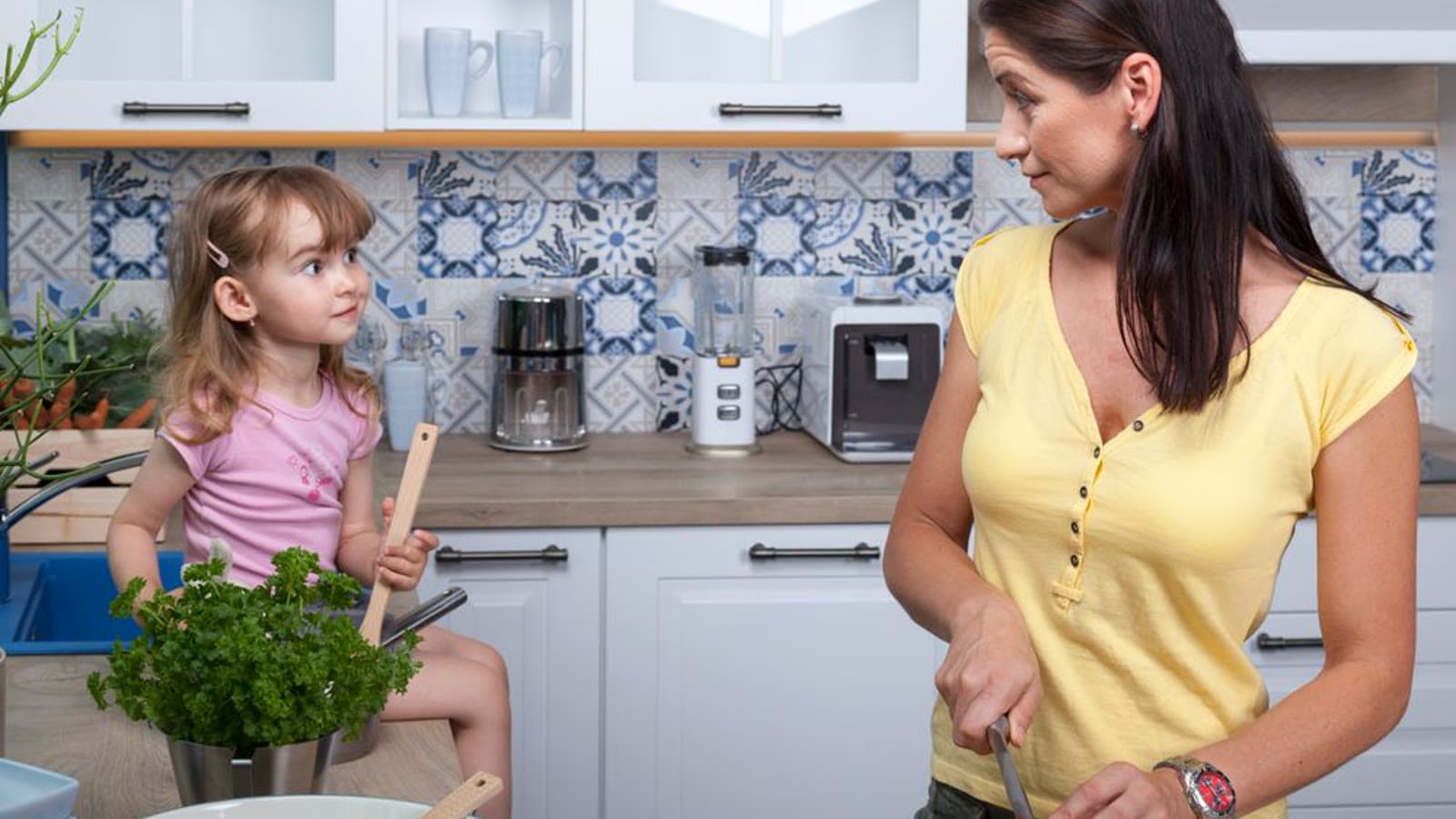 A mother and child cooking together at a kitchen counter