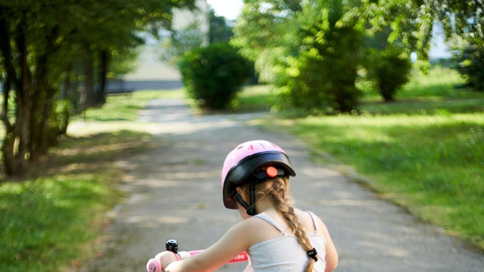 A young girl riding a small bicycle with training wheels in a park
