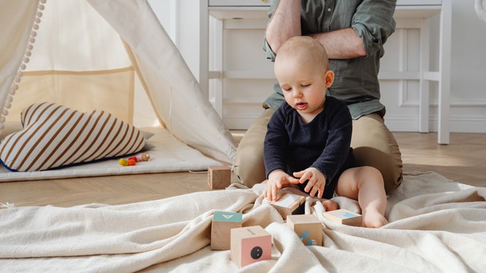 A baby sitting on the floor and playing with wooden blocks