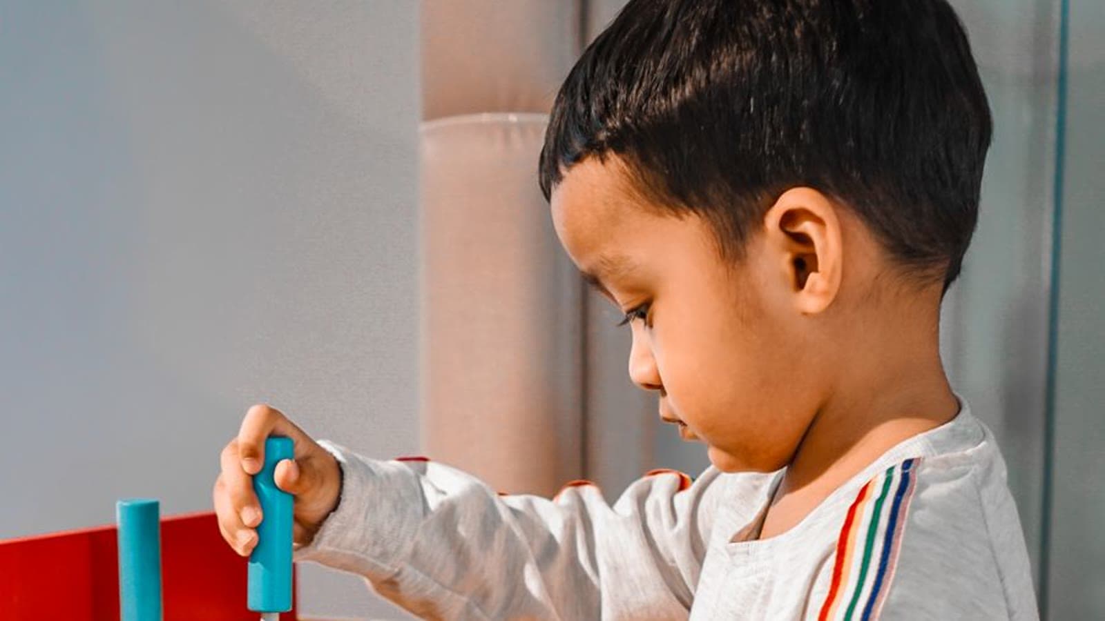 A young child playing at a wooden toy kitchen