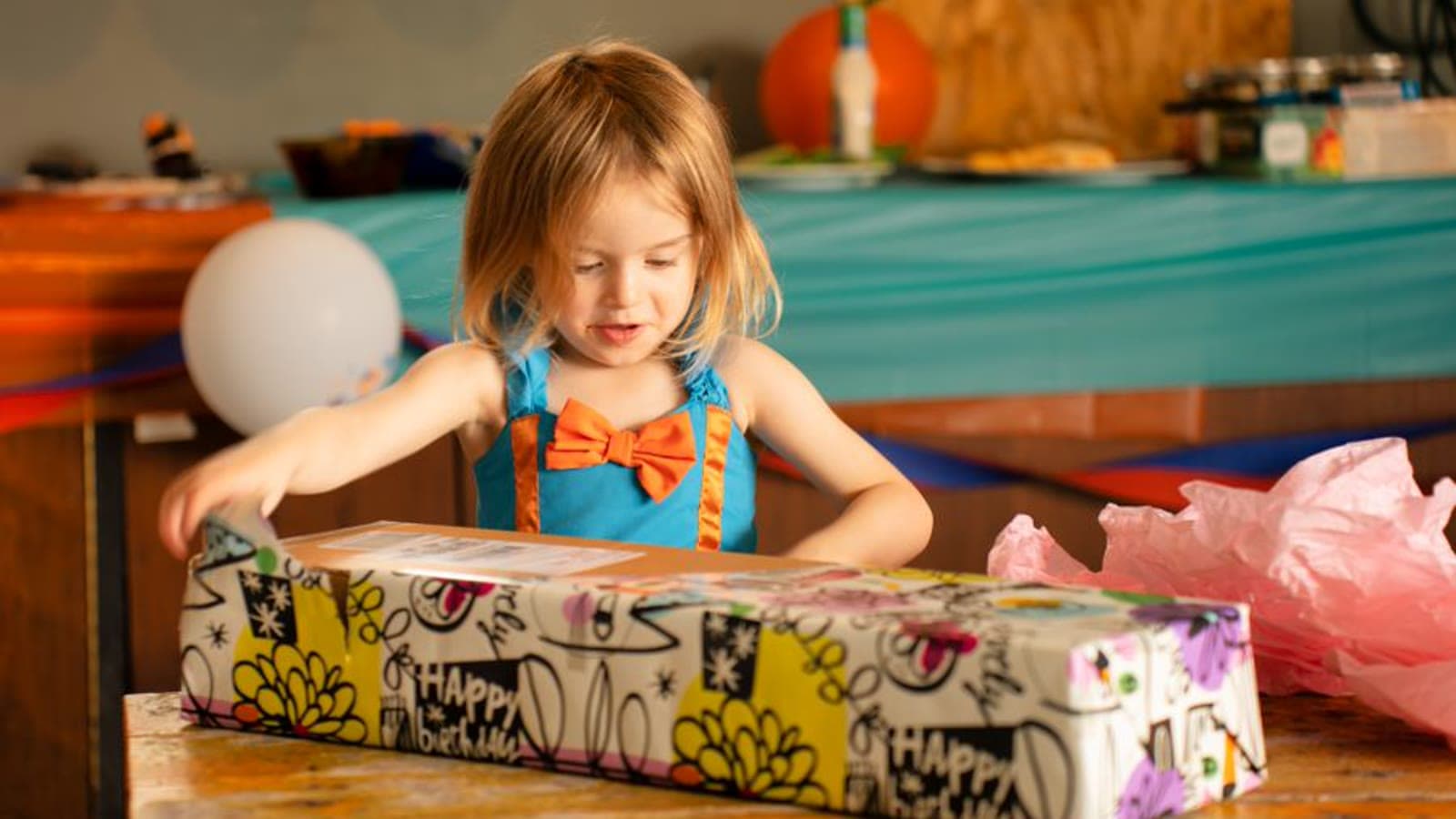 A young girl in a pink dress holding a small wrapped gift