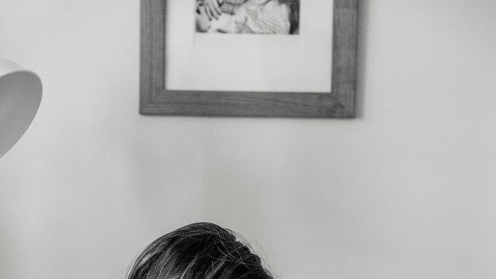 A mother cradling her sleeping newborn on a couch