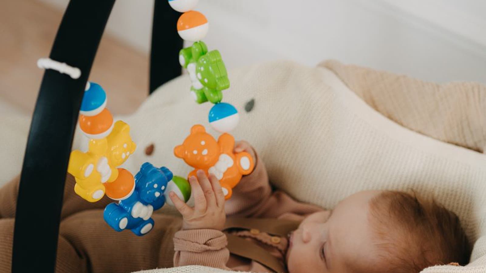 An infant sleeping in a car seat with colorful hanging toys