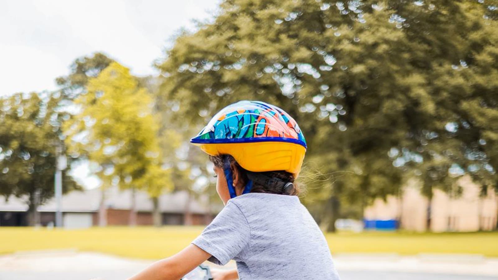 A child riding a bicycle while wearing a blue bike helmet