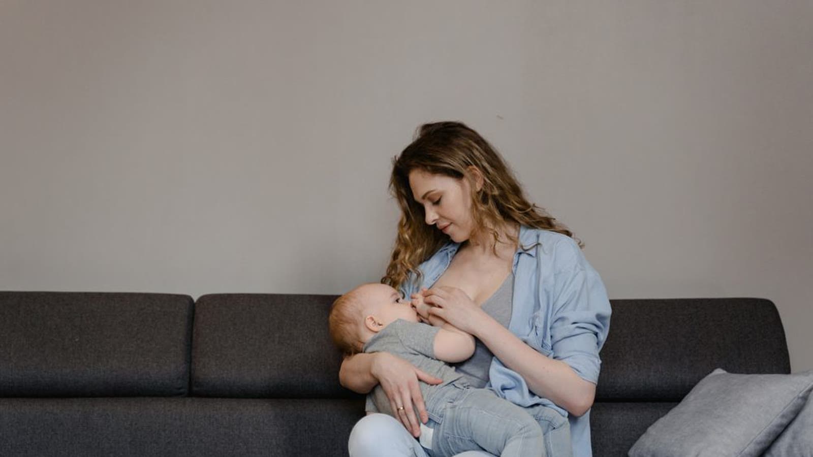 A mother breastfeeding her baby while sitting on a couch