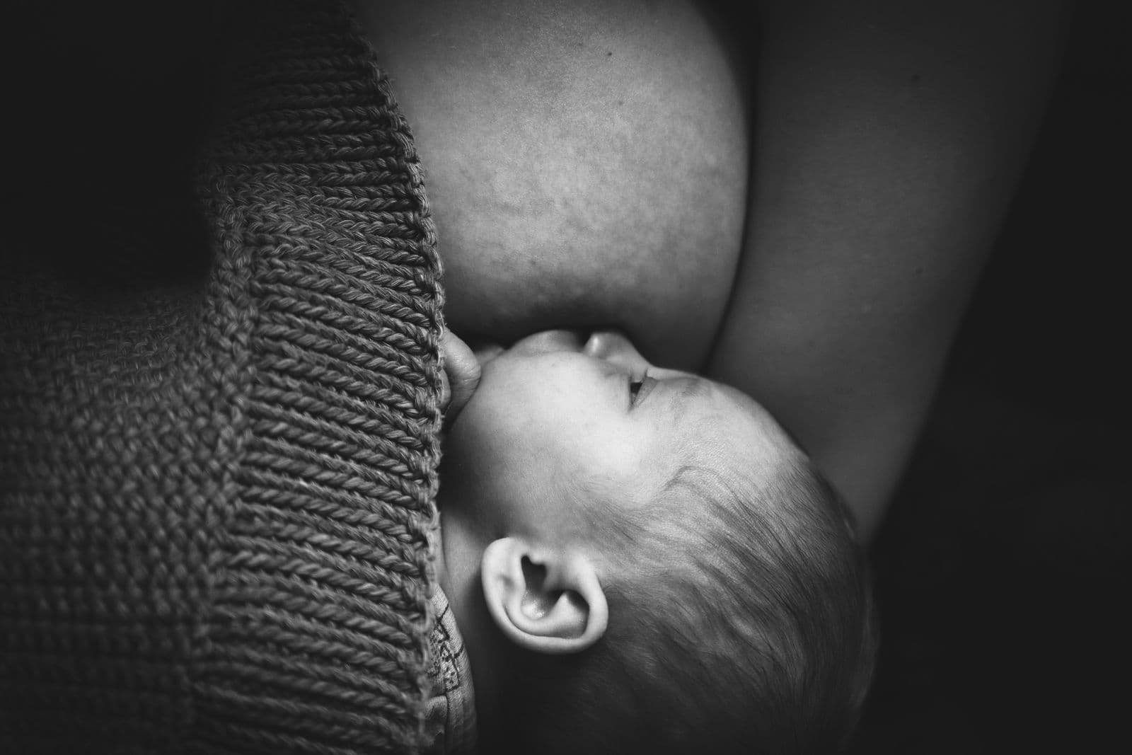 A parent feeding a newborn in a chair, the kind of supervised awake feeding a nursing pillow is actually for