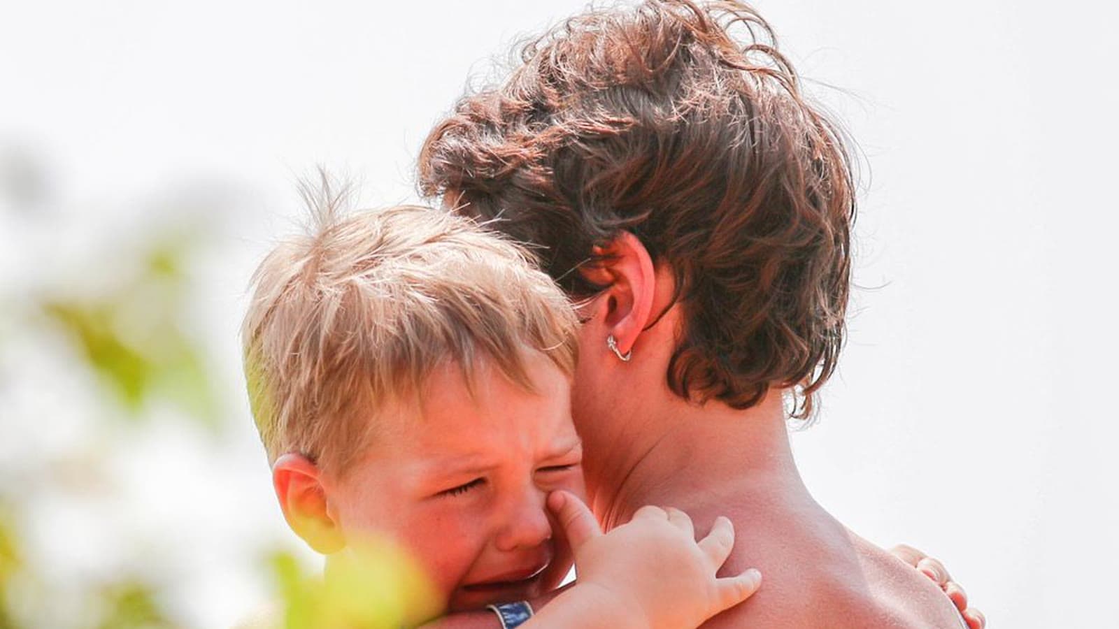 A parent comforting a crying young child outdoors