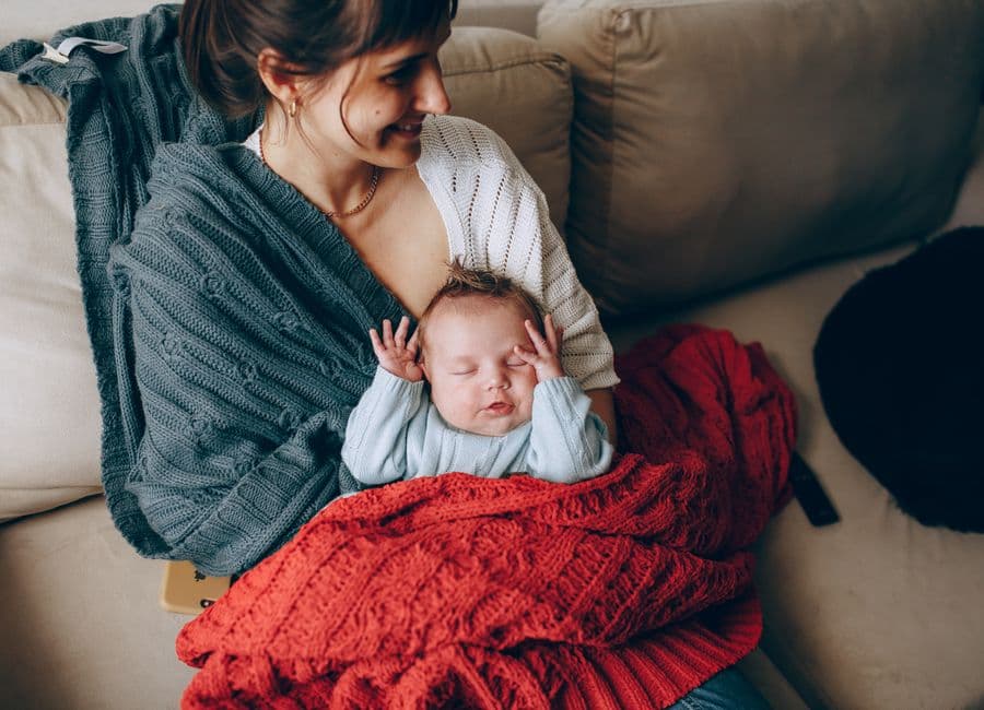 A new mother sitting with her baby, looking worried