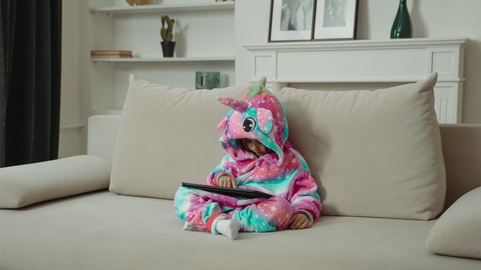 A young child sitting on a sofa and using a tablet