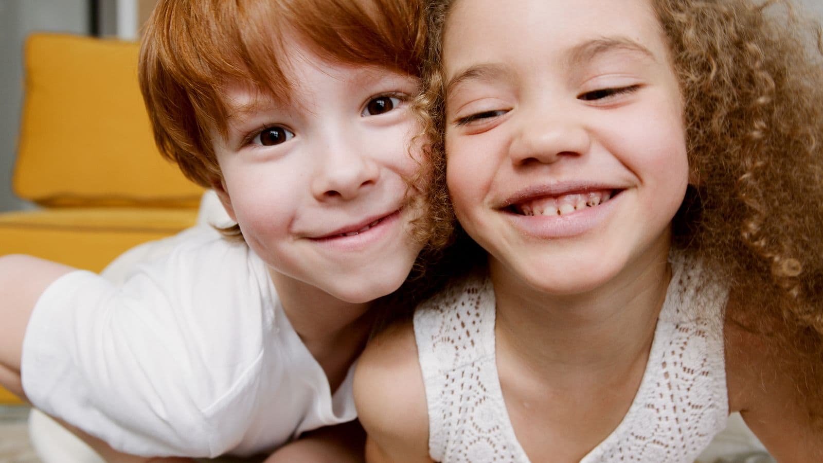 Two young siblings sitting together indoors
