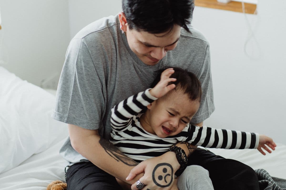 A parent gently comforting an upset toddler