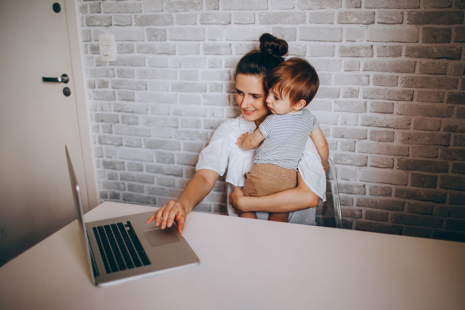 A parent working on a laptop with their baby