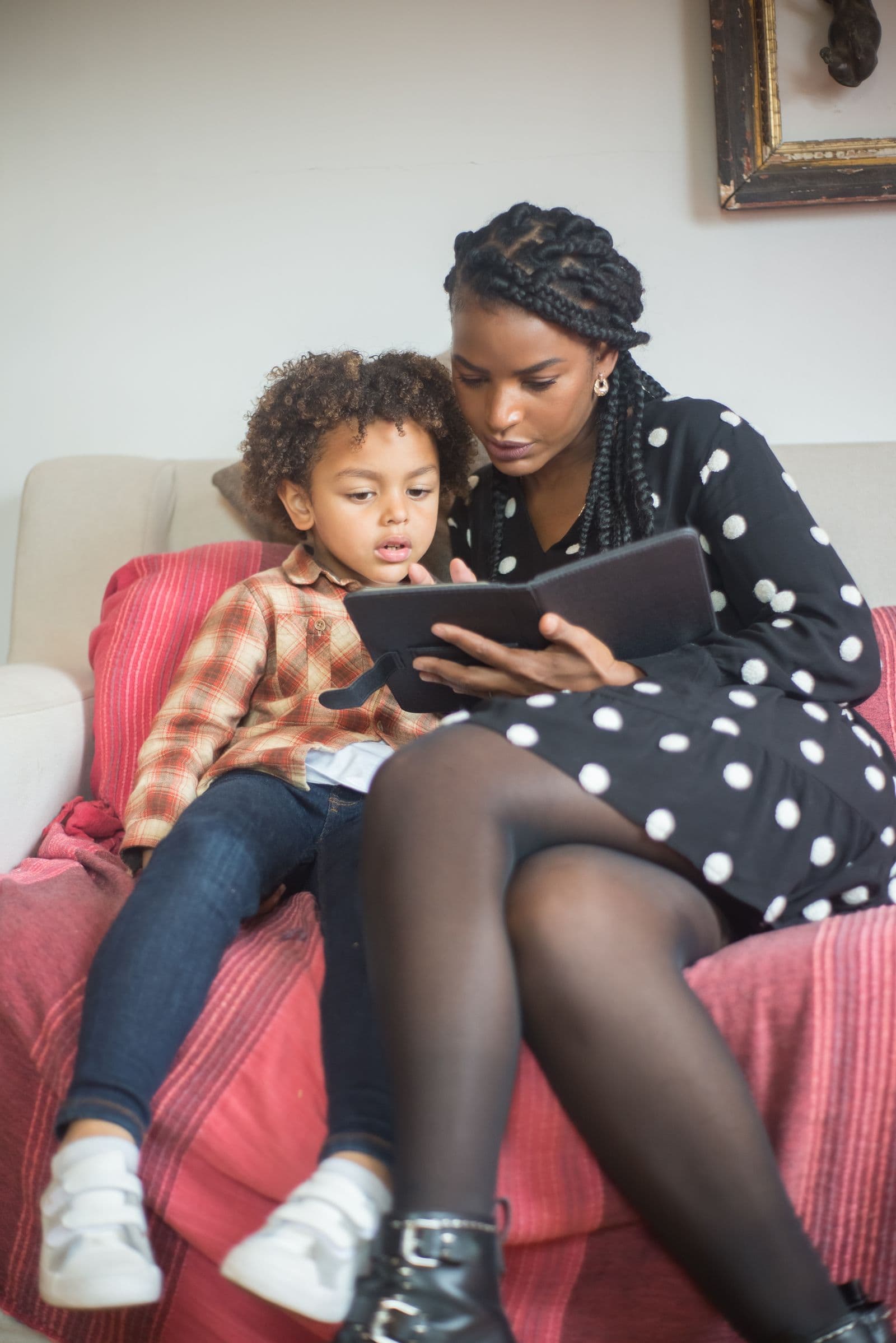 A parent and child looking at a tablet together on the couch
