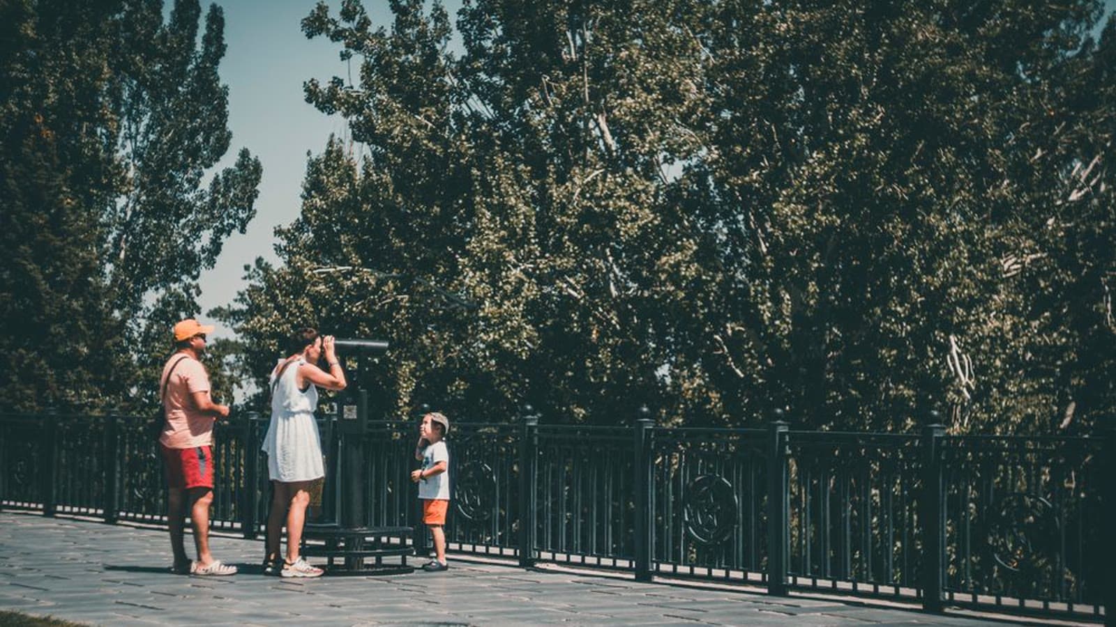 A family with a child looking through a telescope in a park