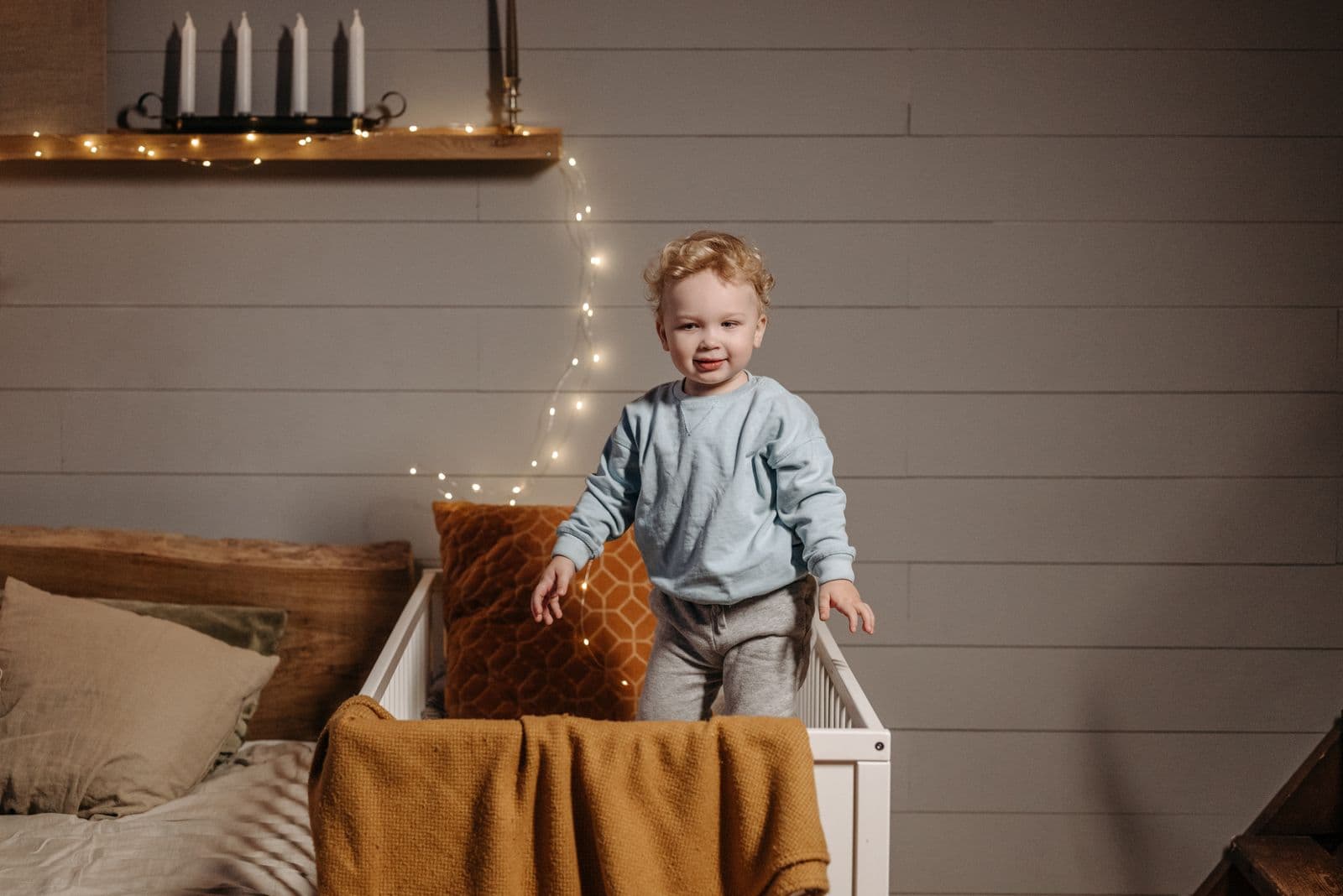 A toddler standing in a crib at night in a cozy nursery