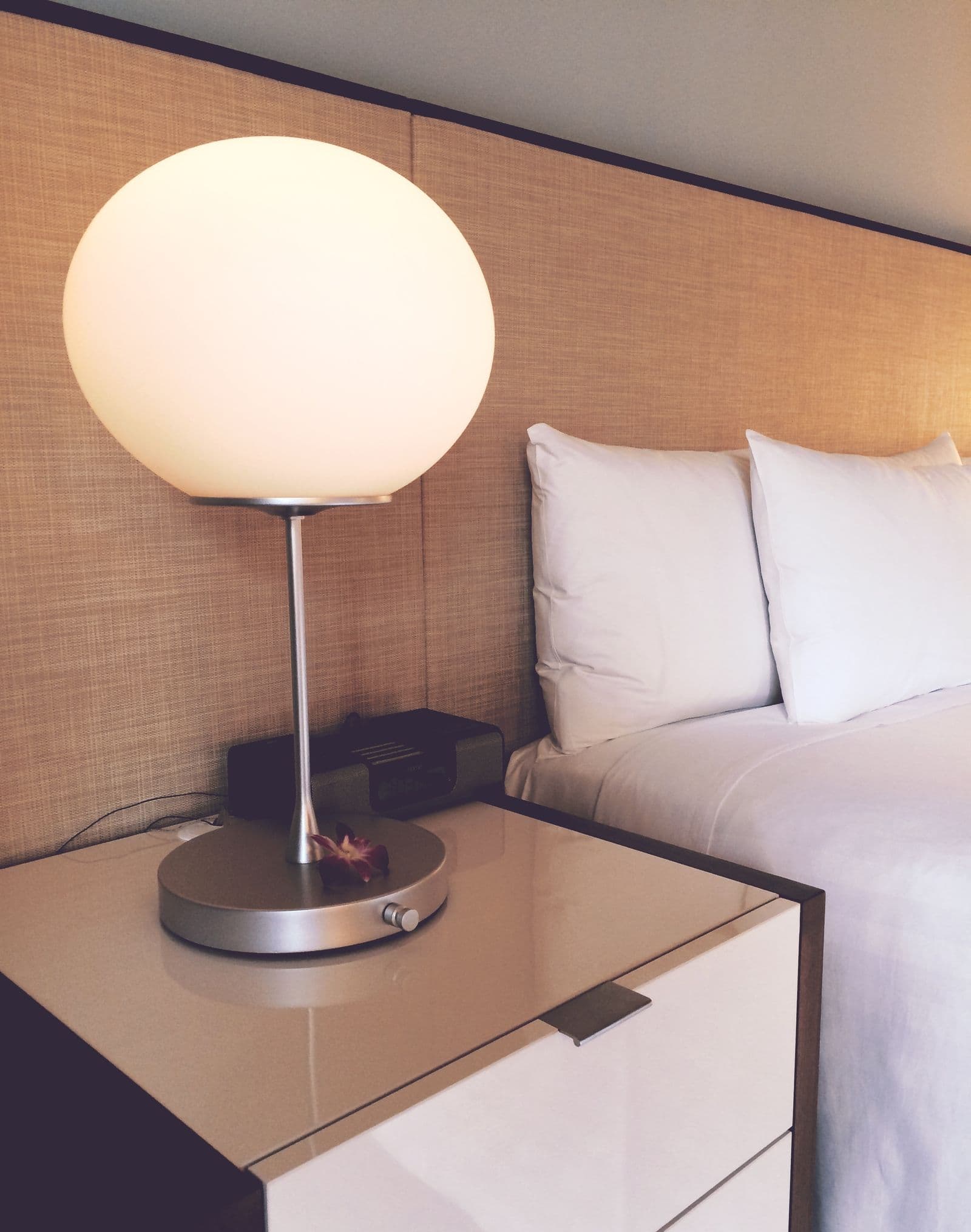 A made hotel bed with layered pillows and a folded blanket in a softly lit room