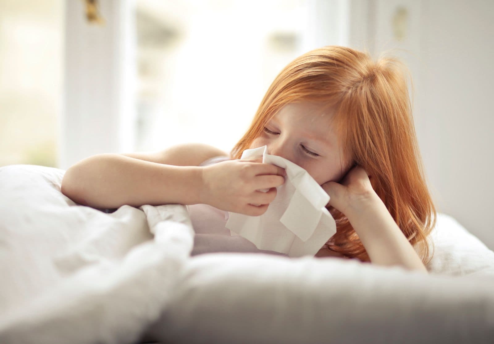 A child resting in bed with a tissue